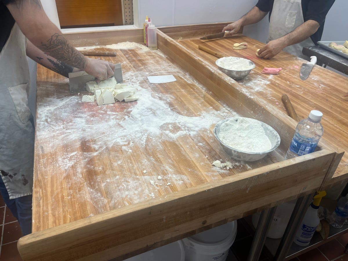 Two bakery workers making dough at flour-dusted table at Los Portales
