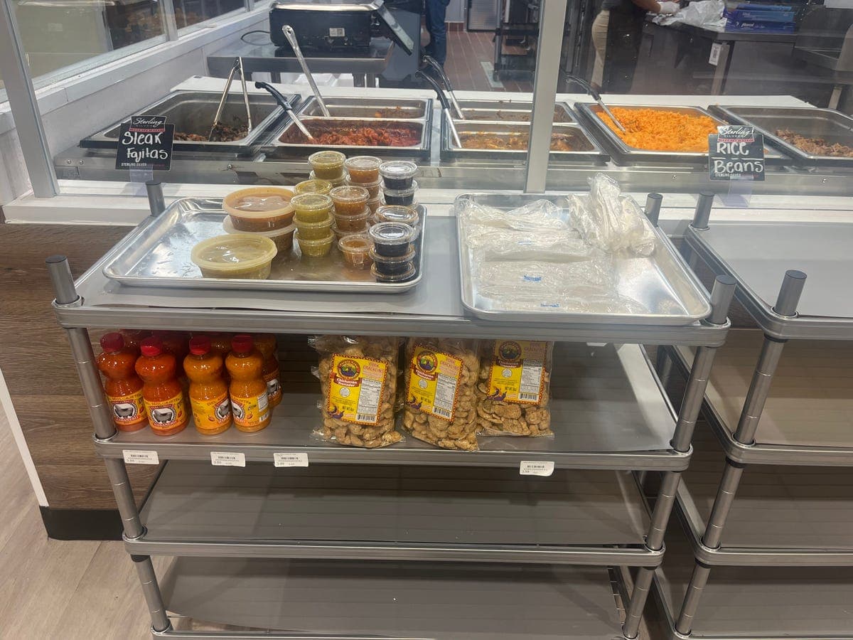 Hot food steam trays with fajitas, rice, beans, and salsas at Los Portales