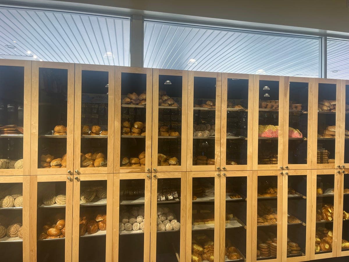 Glass-front wooden panadería cabinets filled with pan dulce at Los Portales